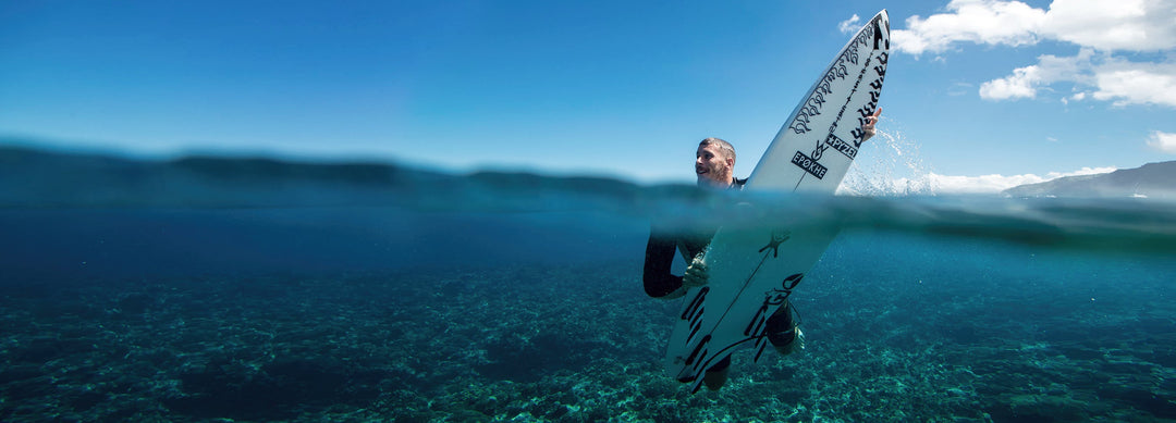 Man half in and half out of water on a surfboard