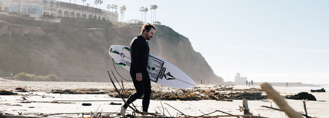 man walking on beach with surfboard